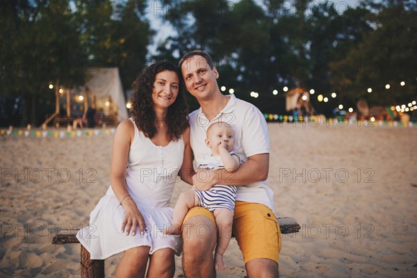 Theme of family summer holidays on the beach. Caucasian man and woman dad and mom hug a small baby
