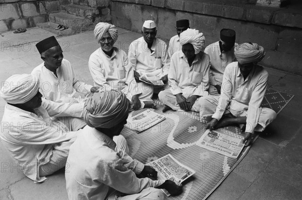 Rural people seating in group and reading news papers, Munagoli village, Bijapur district,