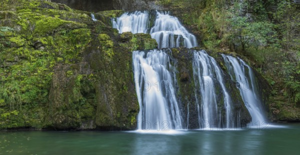 Waterfall from the source of the Lison in a haven of peace with its waterfall surrounded by forest.