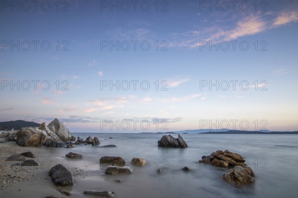 View through rocks on a sandy beach into the sunset. Landscape shot with view to the horizon over