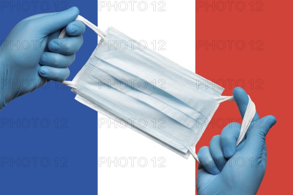 Doctor holding respiratory face mask in hands in blue gloves on background flag flag of France or