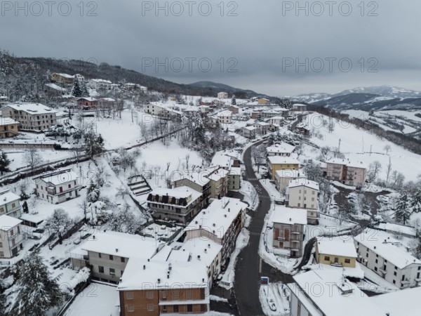 Aerial view of bore, a village in the province of parma covered by snow in december 2024,