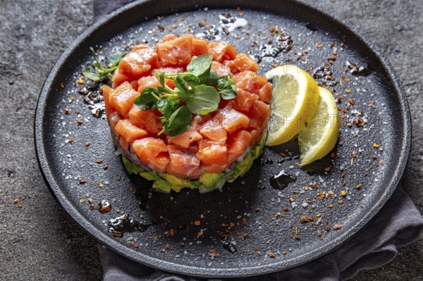 Food, Raw salmon, avocado purple onion salad served in culinary ring on black plate. Black concrete