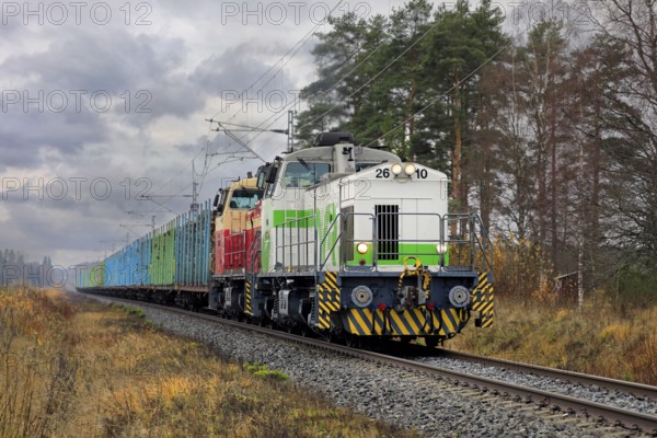VR freight train with two diesel locomotives and carriages full of wood logs on the move on a day