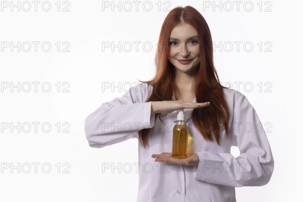 A smiling young woman in a lab coat showcases an innovative hair care product, highlighting beauty