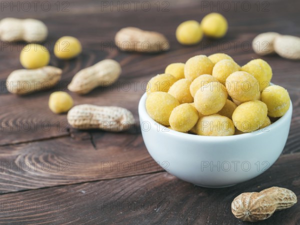 Peanut snack for beer, wine, party bar. Salted peanuts in yellow cheese glaze on brown wooden table