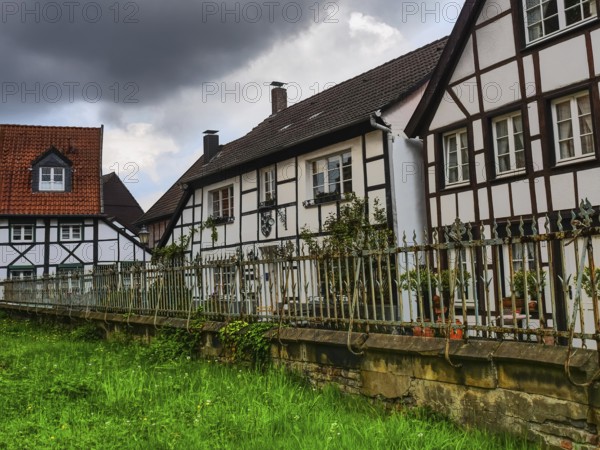 Large half-timbered houses with a fenced garden and clouds in the sky, Herten, North