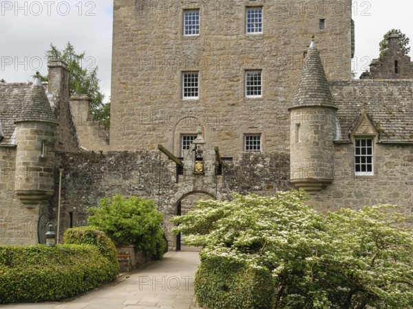 An old castle with stone walls, towers and an entrance surrounded by green plants, inverness,