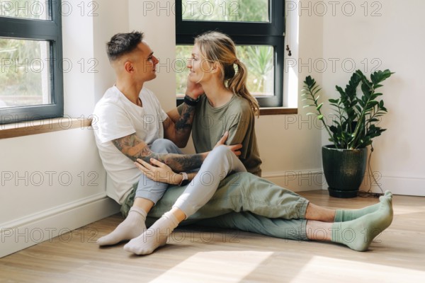 Junges, glückliches Paar in ihrer neuen Wohnung, das sich umarmt, während es bei einem Date auf dem