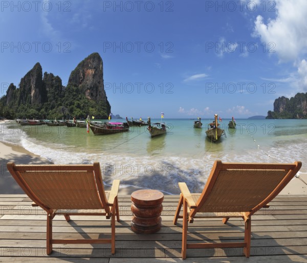 Cozy beach rest. Two wooden chaise lounges and small bedside table on a wooden scaffold. Native