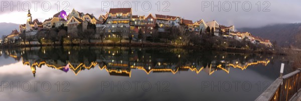 Christmas illuminated house facade of Frohnleiten reflected in the river Mur, panoramic view,