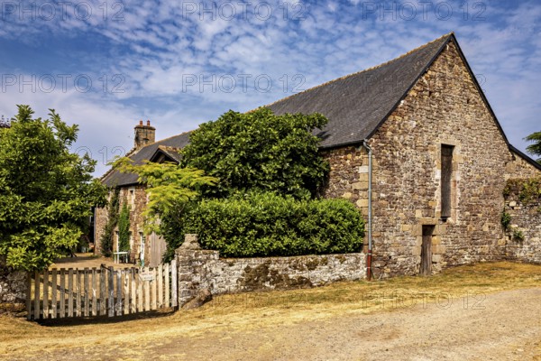 Rural stone house with a small wooden fence and green bushes under a clear sky, The Abbey de La