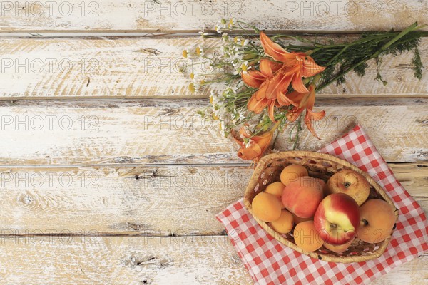 Summer berries and fruits on a wooden background with lilies and daisies, harvesting in the