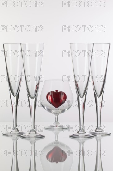 Different glasses and red heart on a glass plate