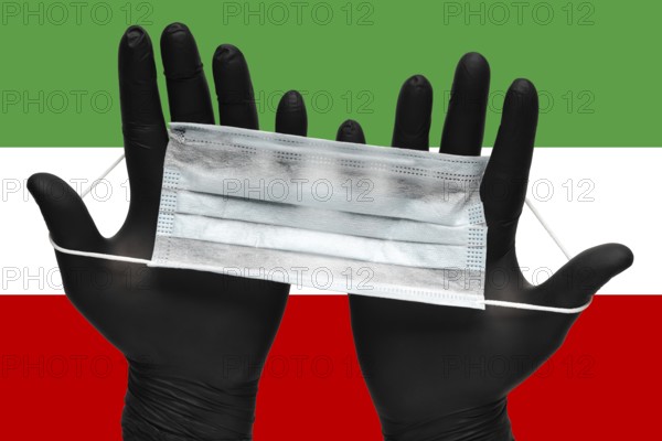 Doctor holds respiratory face mask in hands in black medical gloves on background colors flag of