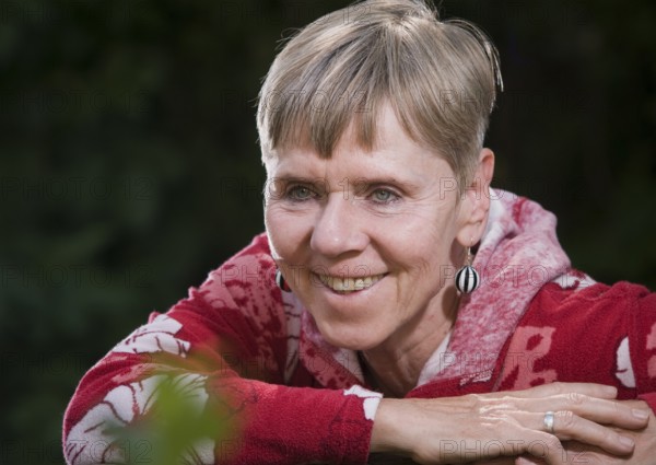 Portrait of an elderly woman on a park bench in summer with her upper body turned backwards over