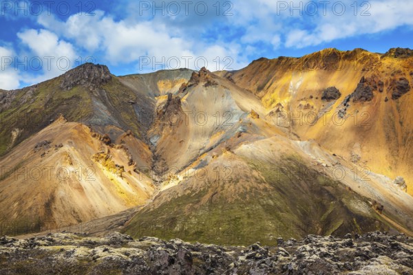 Multi-colored mountains from rhyolite are lit with the July sun. Travel to Iceland in the summer.