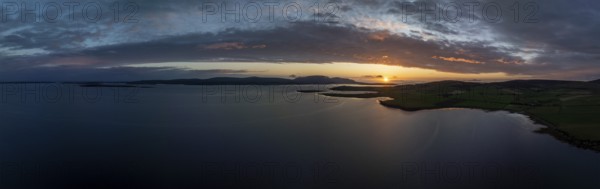Sunset with cloud band on the coast of Scapa Flow with view to the island of Hoy, drone shot,