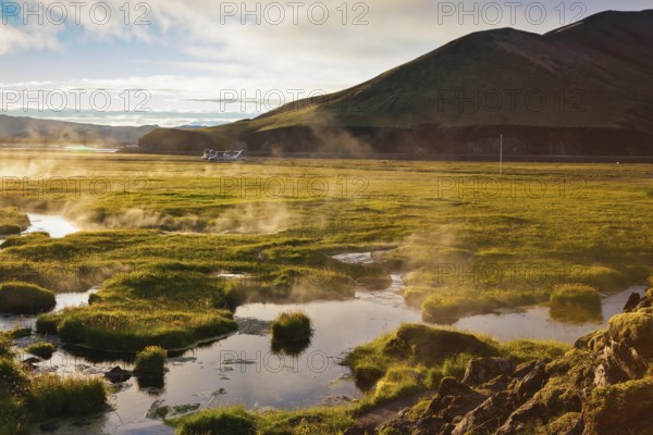 Above the source of thermal water steam rises. White nights in Iceland. Sunrise Park
