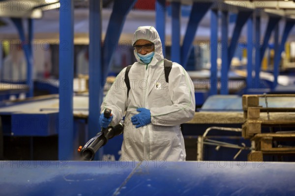 Sofia, Bulgaria - 7 April, 2020: Worker sprays disinfectant outside of ? food market against the