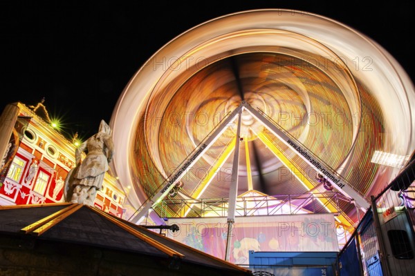 Stone sculpture, miner's fountain in front of Ferris wheel, long exposure, night shot, Leoben,