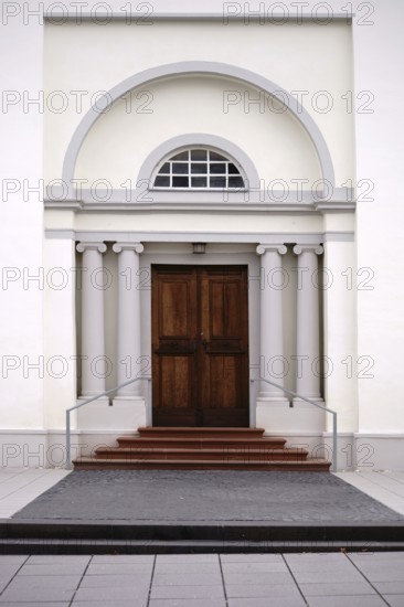 The entrance of a newly built and modern church with an entrance door with a round arch and white