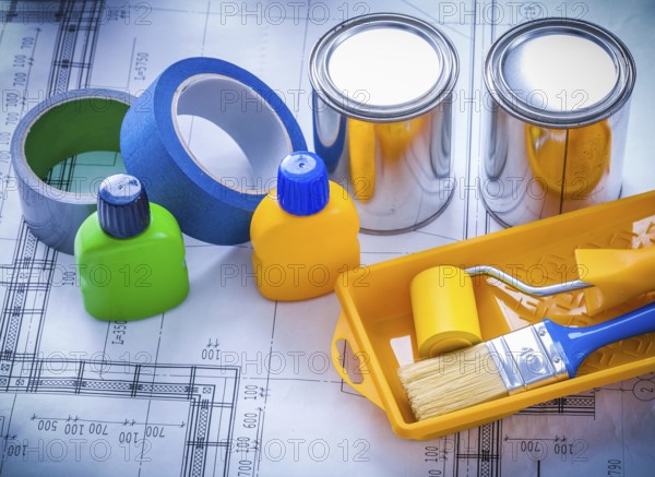 Blueprint with paint brush tray roller cans bottles and household tapes close up image construction