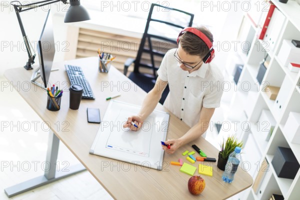A young man in a white shirt and light jeans is working in a bright office. photo with depth of