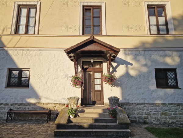 Rustic old building facade with porch and a charming wooden door, framed by two side windows and a