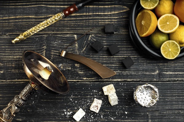 Stylish Smoking hookah and basket with lemon, lime and orange on wooden background. Top view. Flat