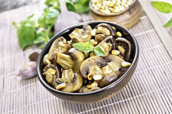 Champignons baked with oregano, wine, garlic, lemon and pine nuts in bowl on background of brown