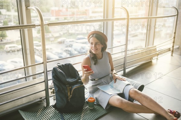 Theme of tourism and travel of young student. Beautiful young caucasian girl in dress and hat sits