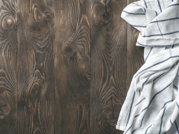 View from above on brown wooden table with linen kitchen towel or textile napkin. Blue tablecloth