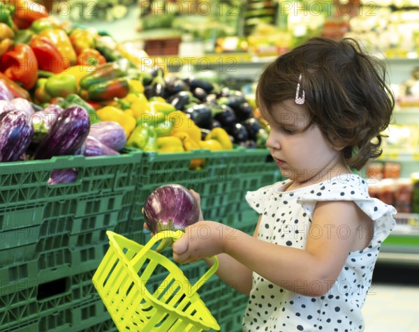 Child shopping eggplants in supermarket. Concept for buying fruits and vegetables in hypermarket.
