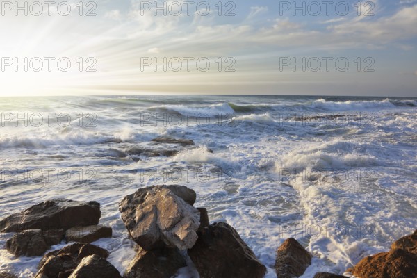 Magnificent sunset on Mediterranean sea. Storm waves break about breakwater stones on quay. Tel