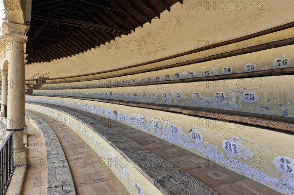 Bullring of Ronda, Plaza de Toros, Numbered rows of seats in an arena with old-style wood and stone