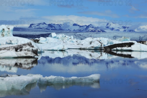 Sunrise. Blue and emerald icebergs and ice floes are reflected in smooth water of the Gulf