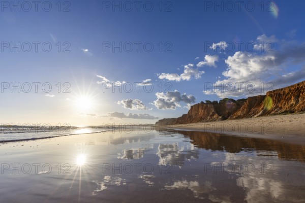 The golden sandy beach of Praia da Falésia, crystal clear sea water at low tide with the reflection