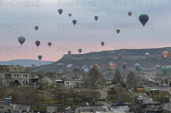 A picture of hot air balloons flying over the Goreme Historical National Park and the town of