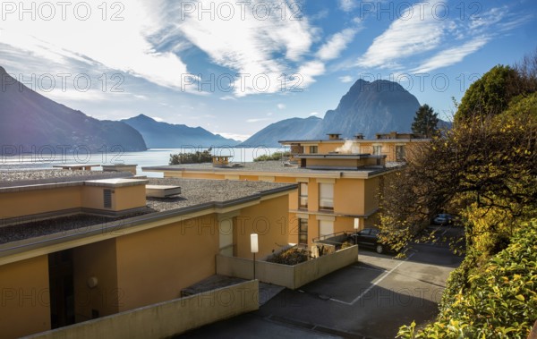 Amazing view of 4-story apartment buildings on the shores of Lake Lugano and a park on the coast
