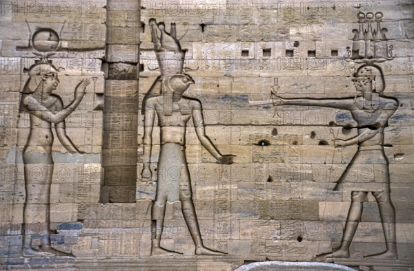 Scanned historical colour photo of relief-like pharaohs and gods carved into a wall in the temple