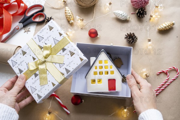 Key to house with keychain on cozy home in gift box with Christmas decor packaging. Pack present