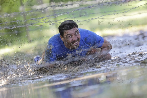Sofia, Bulgaria - July 9, 2016: A participant is crawling through water under electrified wires at