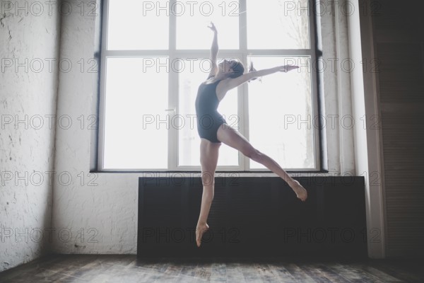 Plasticity slim woman dancing near window. Professional dancer enjoy dance. Lady Dancer Training