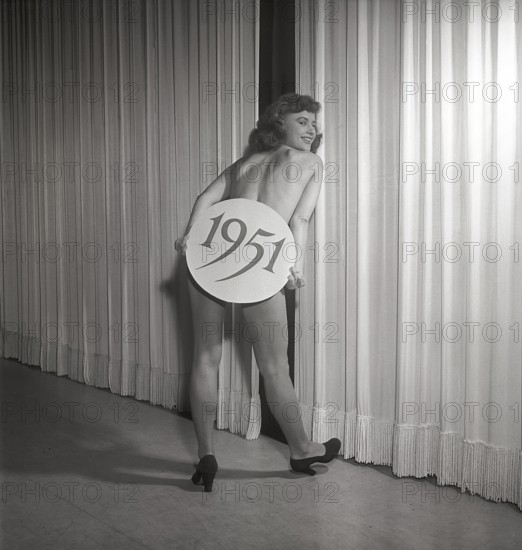 Ballet girl in the 1950s. A young woman on stage holding a sign with the year 1951 printed on it.