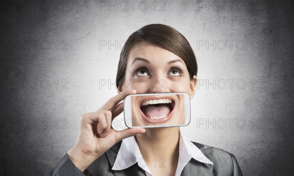 Portrait of young woman covering her mouth with smartphone. Businesswoman showing mobile phone with
