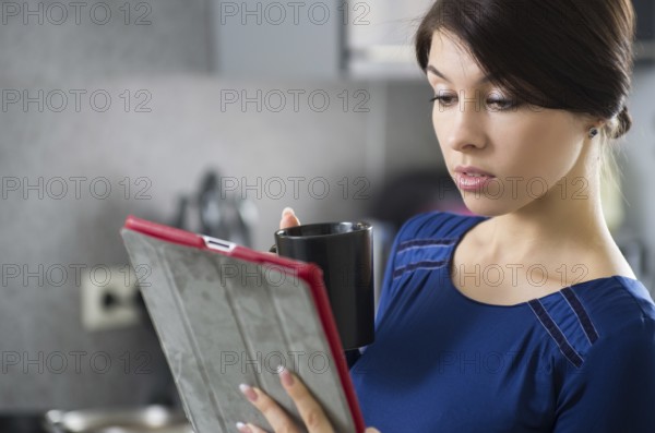 Portrait of young attractive caucasian brunette housewife at kitchen. Morning with cup of coffee