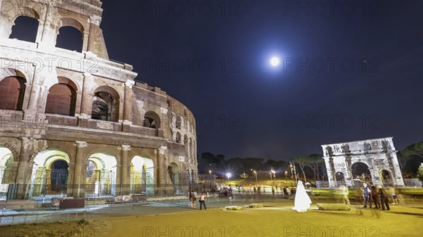 Roman Colosseum and Constantine Arch by night with tourists and photographers with a bride for