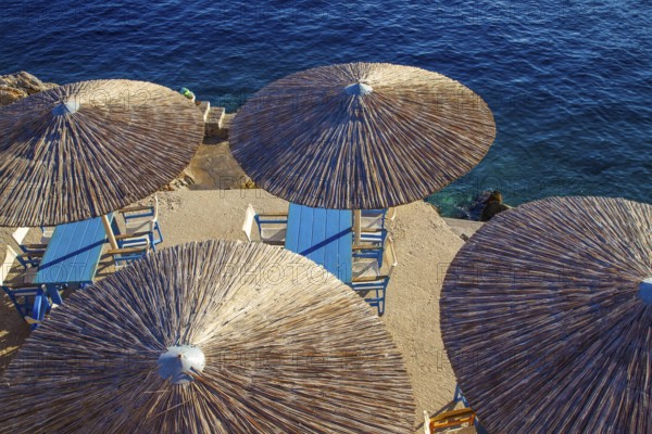 Thatched round roofs of awnings in a small cafe and water of the Mediterranean Sea on the amazing