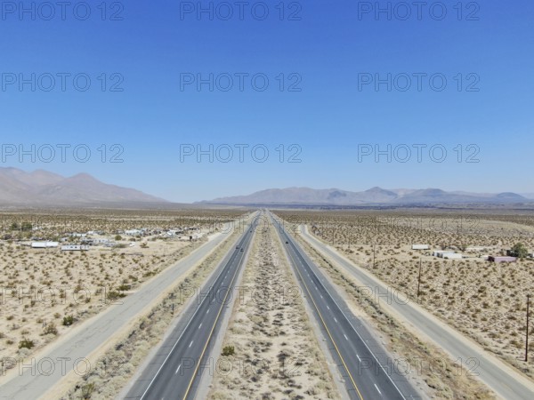 Aerial view of road in the middle of the desert under blue sky in California's Mojave desert, near
